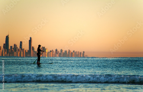Single paddler against the Gold Coast skyline at sunset.
