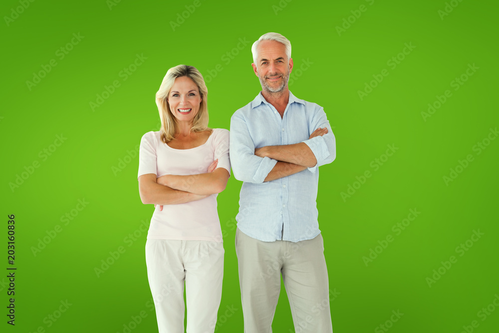 Smiling couple standing with arms crossed against green vignette Smiling couple standing with arms crossed against green vignette
