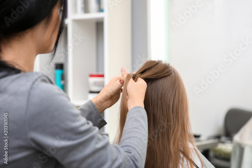 Professional female hairdresser working with little girl in salon