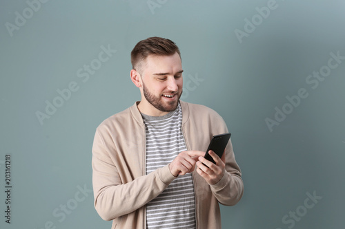 Portrait of confident young man with mobile phone on color background