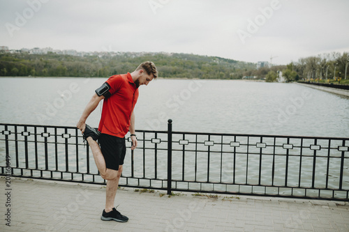 Healthy blonde male doing warming exercises before daly sprint in the park. © Strelciuc