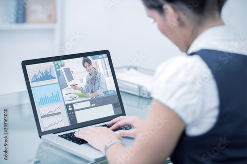 Business interface against business worker using laptop at desk