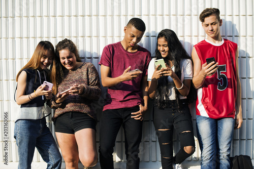 Group of young teenager friends chilling out together using smartphone social media concept photo