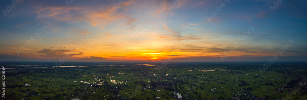 Naklejka premium Panorama Top view Aerial photo from flying drone over village in Thailand.Top view beautiful Sunset.Sunrise with cloud over rice field.
