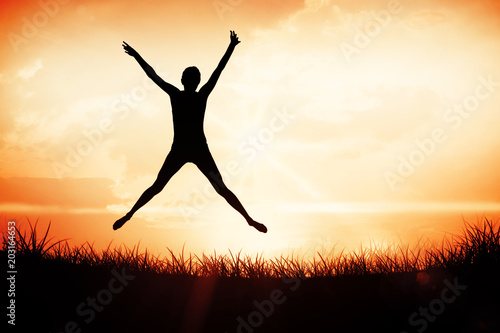 Full length of a sporty young woman jumping against orange sunrise