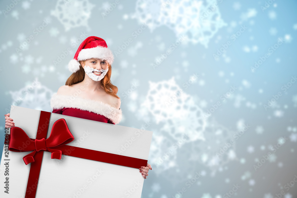 Festive redhead in foam beard holding poster against red christmas ribbon Festive redhead in foam beard holding poster against red christmas ribbon