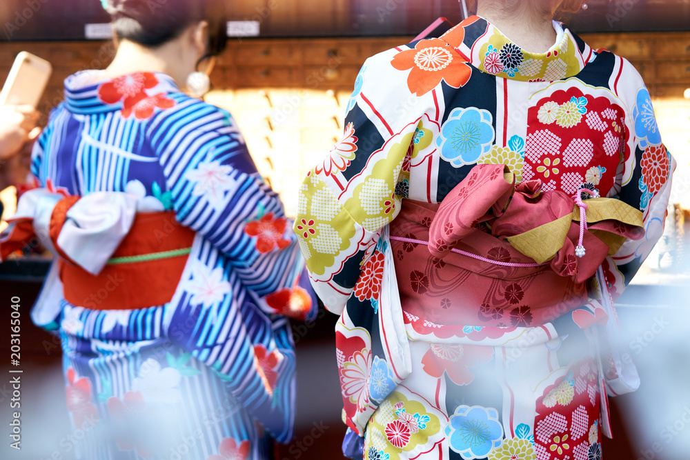 Fototapeta premium Young girl wearing Japanese kimono standing in front of Sensoji Temple in Tokyo, Japan. Kimono is a Japanese traditional garment. The word