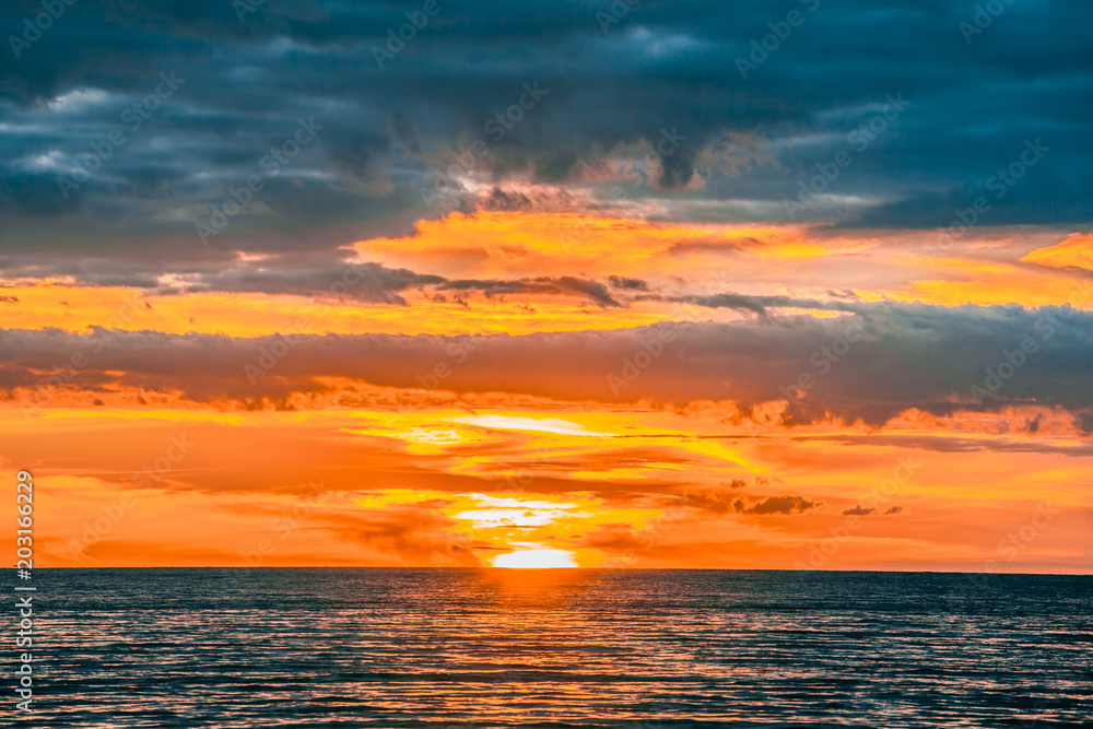 Burning orange sun almost under the horizon - beautiful minimalist seascape