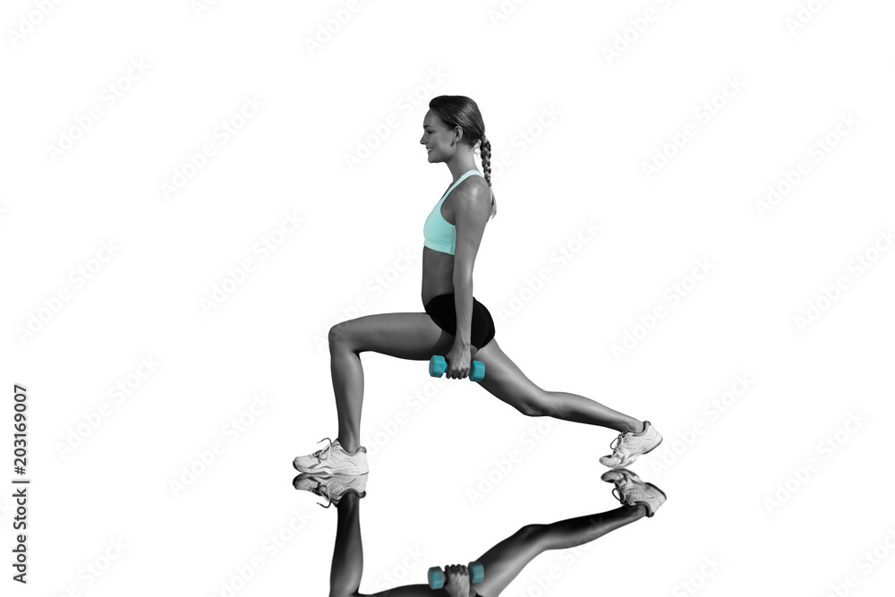 Fit woman doing weighted lunges on the beach against mirror