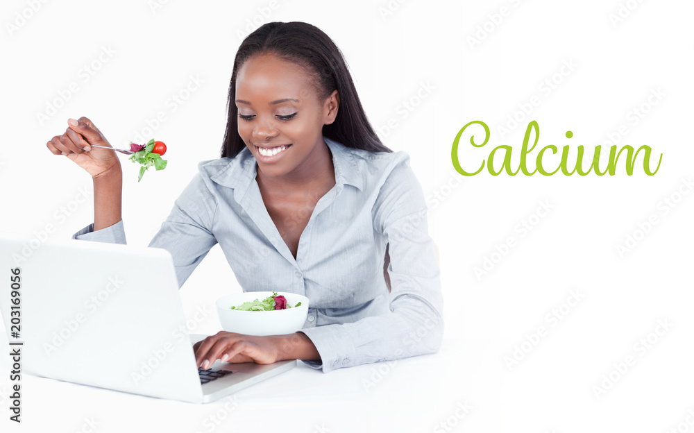 The word calcium against young businesswoman working with a notebook while eating a salad The word calcium against young businesswoman working with a notebook while eating a salad