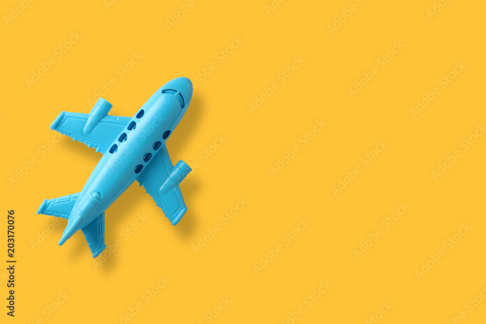 Naklejka premium blue plastic toy plane on yellow background with space 