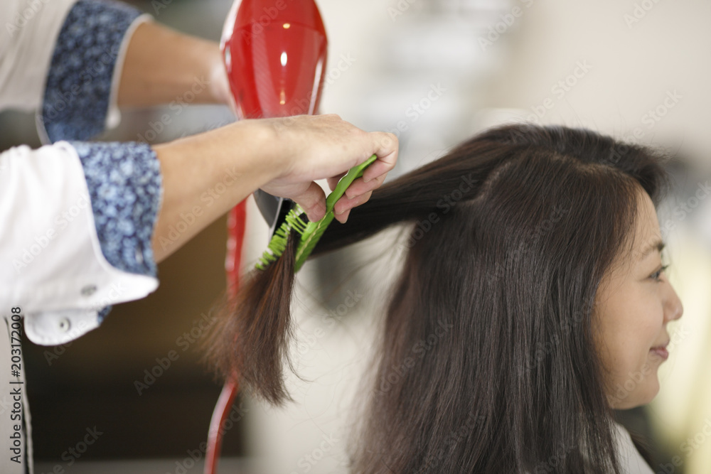 Naklejka premium 美容院で髪を綺麗にしてもらう女性