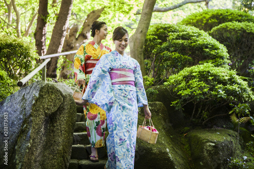 和服を着ている女性たちは日本庭園を散策している