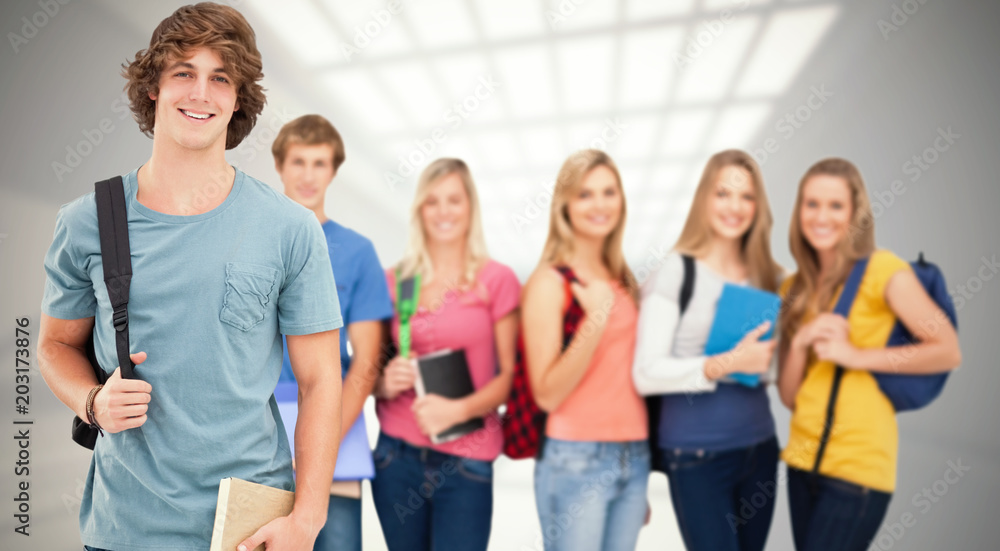 A man standing in front of his friends as he smiles against room with windows at ceiling A man standing in front of his friends as he smiles against room with windows at ceiling