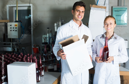 Two smiling employees standing in packaging section on wine manufactory © JackF