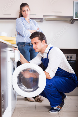 Repairman and woman near washing machine.