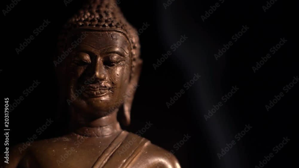 Extreme closeup of sitting Buddha on the left with smoke rising on the right. Extreme closeup of sitting Buddha on the left with smoke rising on the right.