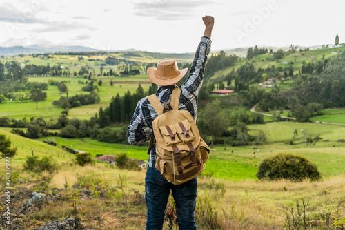 Man on top of a mountain with his hand up