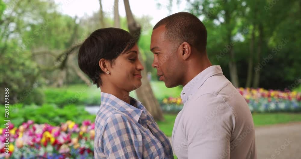 Playful young Black man and woman flirting around in a beautiful garden outside, Youthful happy African-American couple enjoying time together near a colorful garden in the park, 4k Playful young Black man and woman flirting around in a beautiful garden outside, Youthful happy African-American couple enjoying time together near a colorful garden in the park, 4k