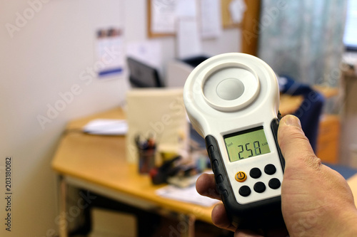 Measuring office lighting with lux meter. Lighting ergonomics on workstation.