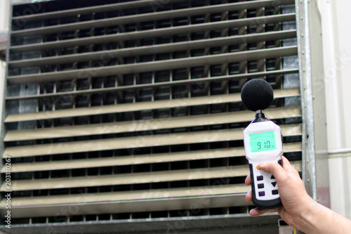 Sound level meter measuring the noise of industrial ventilation unit.