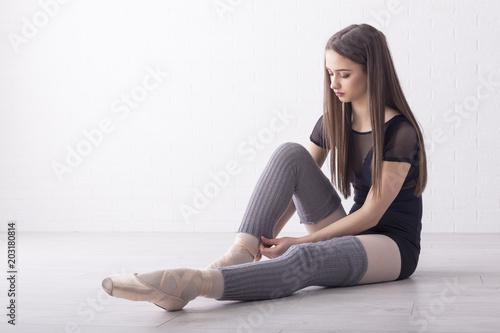 Beautiful ballet dancer sitting on the floor and prepare for performance