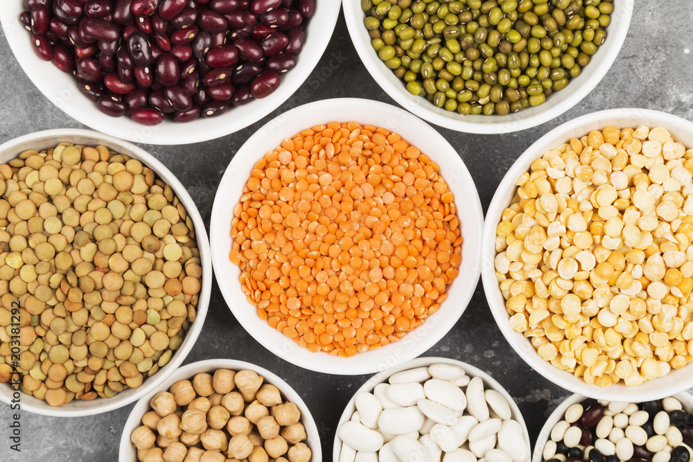 Assortment of beans (red lentil, green lentil, chickpea, peas, red beans, white beans, mix beans, mung bean) on gray background. Top view. Food background Assortment of beans (red lentil, green lentil, chickpea, peas, red beans, white beans, mix beans, mung bean) on gray background. Top view. Food background