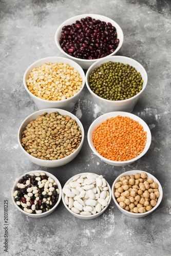 Assortment of beans (red lentil, green lentil, chickpea, peas, red beans, white beans, mix beans, mung bean) on gray background