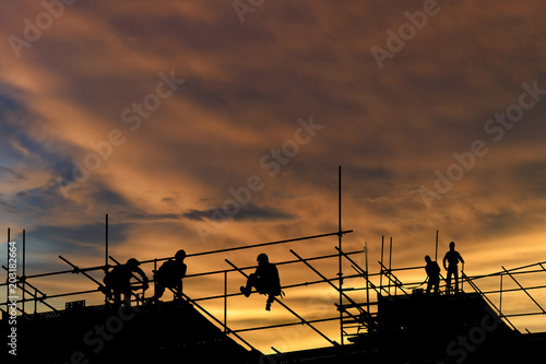 Silhouette construction worker , tower cranes build large residential buildings at construction site industry .