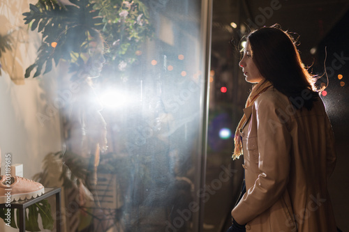 Girl brunette near in the shopwindow on the night city street