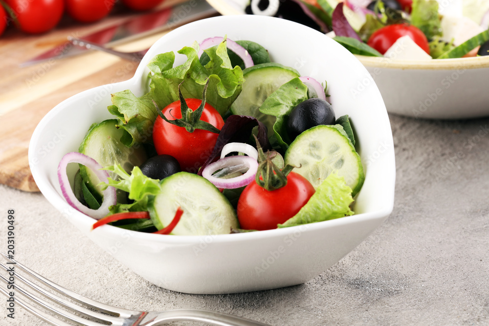 bowl of salad with vegetables and greens, with tomato, cucumber and onions. bowl of salad with vegetables and greens, with tomato, cucumber and onions.
