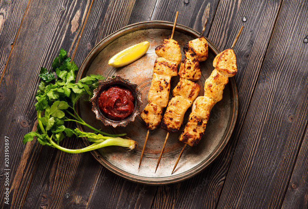 Shish kebab fillet of turkey on bamboo skewers on a metal plate, on a wooden table, top view