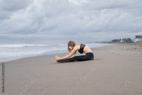 attractive young woman practicing yoga in Caterpillar pose on seashore © LIGHTFIELD STUDIOS