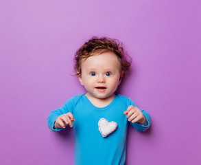 Little infant baby with heart shape toy on purple background
