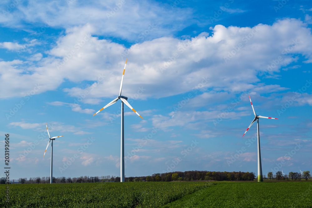 Windräder auf einem Feld drehen sich und produzieren Ökostrom Windräder auf einem Feld drehen sich und produzieren Ökostrom