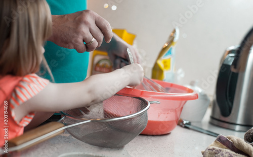 Little girl helps dad in a beautiful kitchen to cook food and wash dishes