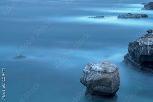 Early morning in La Jolla Cove with ocean soft blue water overlooking big rocks