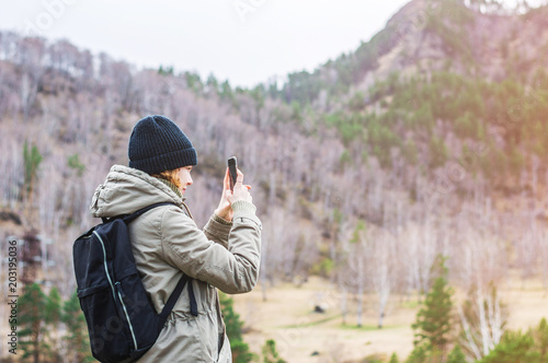 Girl taking photo with phone camera in the mountains