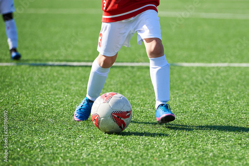 Foot of child football player and ball