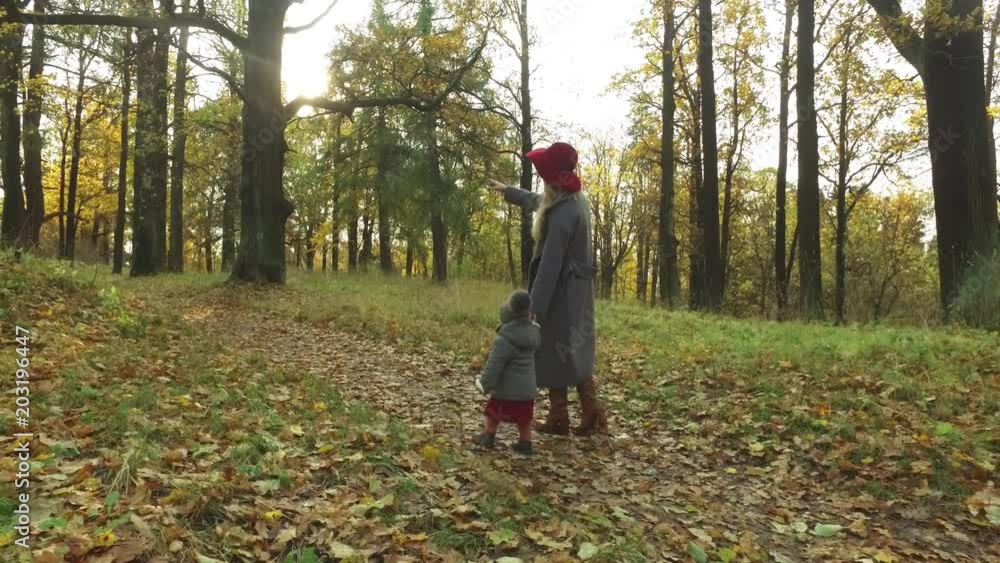 Mom and daughter are walking in the autumn park Mom and daughter are walking in the autumn park