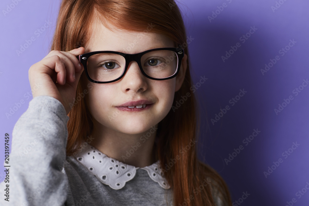 Redheaded girl adjusting glasses, portrait