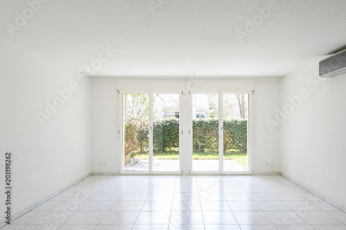 Large windows overlooking the garden in a completely empty room