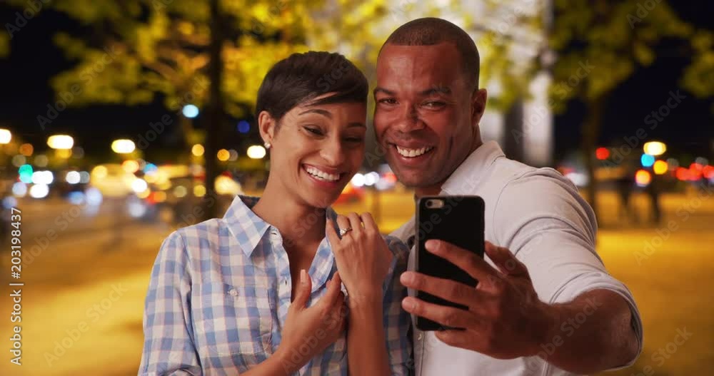 Joyful black couple takes selfies together after their recent engagement while on vacation in Paris, France, Newly engaged African male takes photos with his new fiance with her wedding ring, 4k Joyful black couple takes selfies together after their recent engagement while on vacation in Paris, France, Newly engaged African male takes photos with his new fiance with her wedding ring, 4k