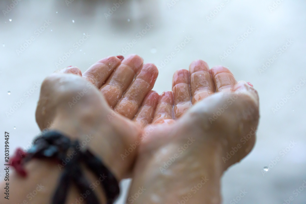 Fototapeta premium Rain drops falling on woman’s hand 
