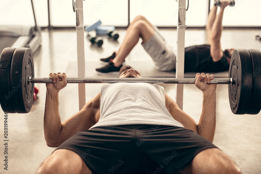 handsome sportsman lifting barbell with heavy weights in gym handsome sportsman lifting barbell with heavy weights in gym
