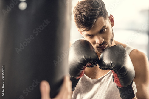 concentrated young boxer looking at punching bag
