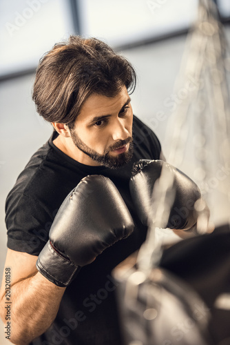 high angle view of handsome young man in boxing gloves training in gym