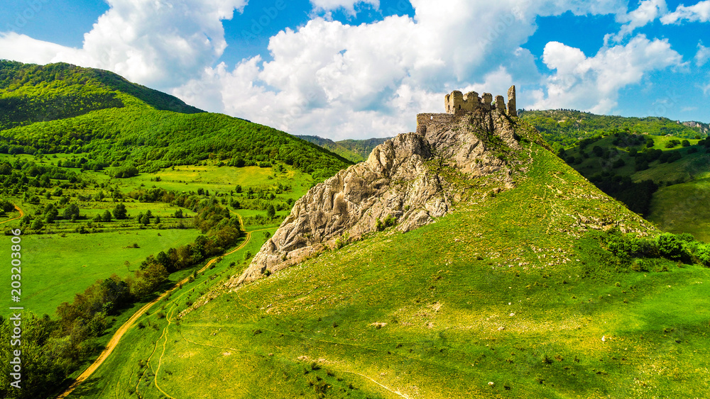 Aerial view of Coltesti Fortress in Transylvania, Romania on a sunny spring day with green hills around and beautiful blue sky with clouds