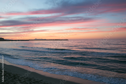 Romantischer Sonnenuntergang und Abendrot in rosa und rot an der Küste Kretas.