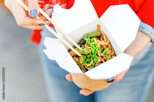 Closeup macro view of a delicious Wok Noodles with greenery in takeout paper box with chop sticks photo